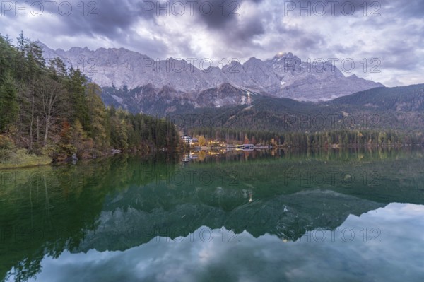 A breathtaking view of Eibsee at dusk, reflecting the towering Bavarian Alps and forested shoreline