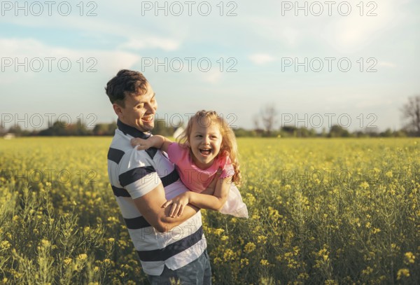 A young father and his little daughter play happily in nature in the summer. Happy parenting and
