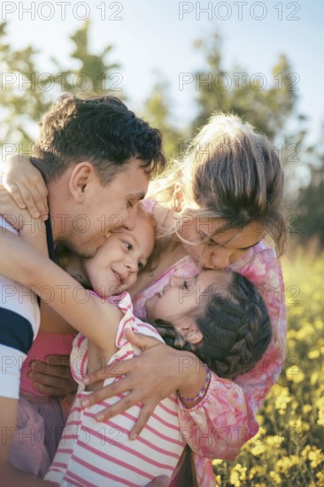 A loving family shares a heartfelt embrace surrounded by golden flowers in the countryside The
