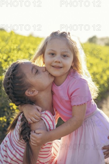 A sweet moment between two sisters as one gives the other a kiss on the cheek Their embrace