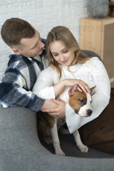 A young couple shares a tender moment with their small dog, conveying warmth and affection in a