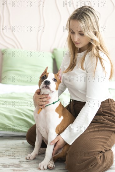 A woman enjoys a quiet moment with her American Staffordshire Terrier in a serene, well-lit living