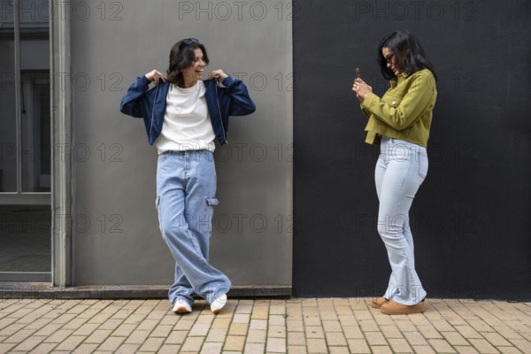 A lesbian couple captures a candid moment outdoors. Both appear happy and relaxed in casual attire