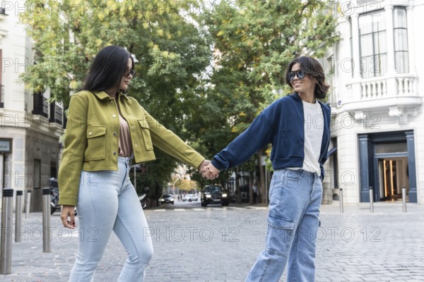A lesbian couple enjoys a delightful walk hand-in-hand through a picturesque urban setting. They