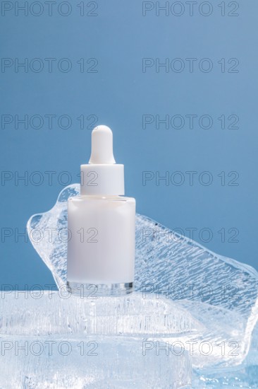 A single serum bottle with a dropper rests on clear ice chunks against a vibrant blue background,