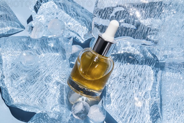 A serum bottle with a dropper is elegantly placed amidst scattered ice cubes, showcasing a