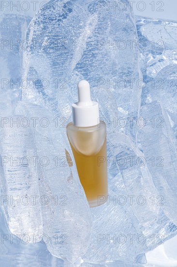 A clear serum bottle with a dropper, encapsulated by shimmering translucent ice cubes, stands out