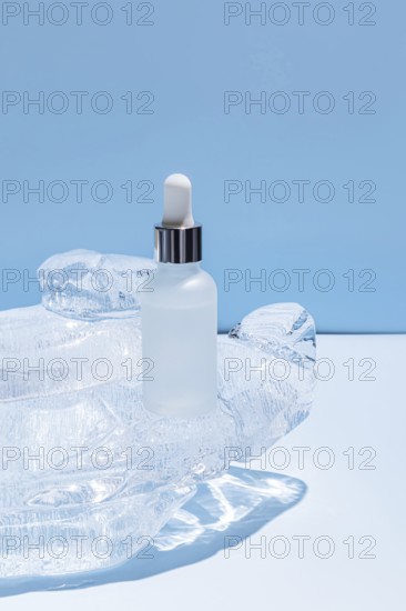 A frosted glass serum bottle with a dropper, resting in a carved ice block on a vibrant blue