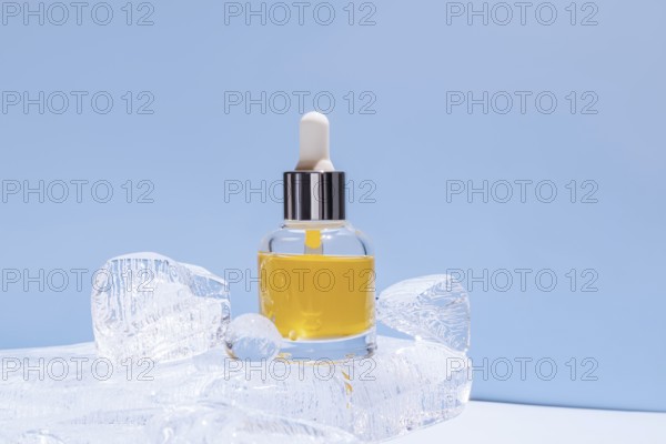 A serum bottle with a dropper, filled with yellow fluid, delicately placed amongst transparent ice