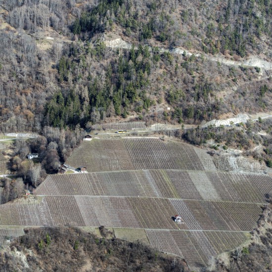 A breathtaking aerial view of Swiss farmland with neatly arranged fields against a rugged hillside.