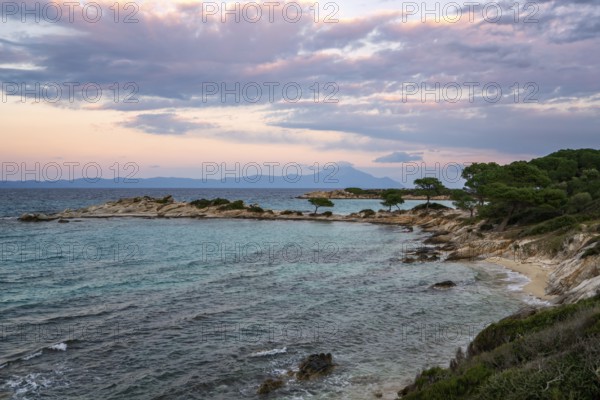 Karydi Beach in southern Greece at sunset, featuring turquoise waters, rocky shores, and scattered
