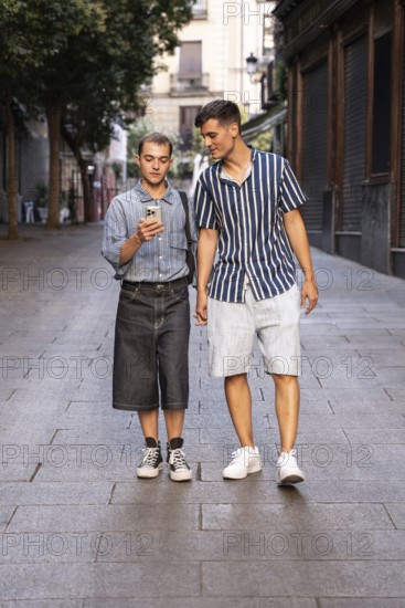 Stylish gay couple walking hand in hand on a quiet street in Madrid, Spain. One checks their