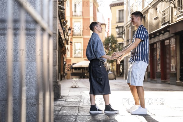 A romantic and joyful moment shared by a gay couple holding hands on a sunny street in Madrid,