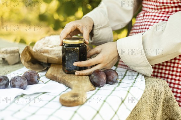 A person prepares canapes using fresh ingredients. The image includes a jar of jam, a loaf of