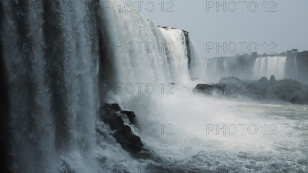 Stunning capture of the powerful Iguazu Falls surrounded by mist and plunging into the river at the