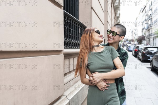 Colombian lesbian couple sharing a joyful embrace in a vibrant city street, showcasing love,