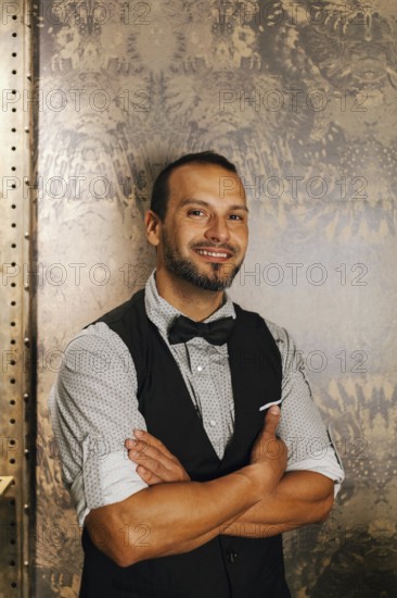 A professional bartender in a stylish cocktail bar setting, dressed in a bow tie and vest, exuding