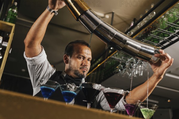 A professional bartender skillfully mixing vibrant cocktails in a stylish bar setting. The image