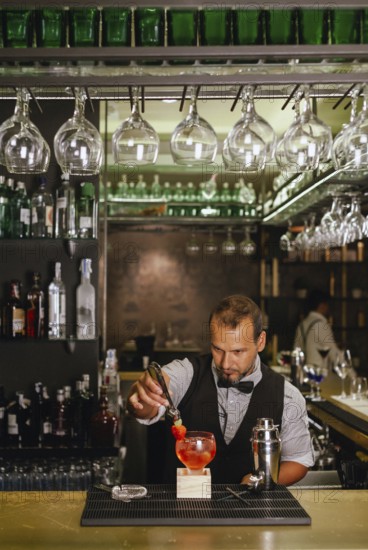 A professional bartender skillfully prepares a vibrant cocktail at an elegant urban bar, surrounded