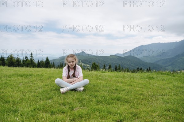 Young girl resting on a grassy hill with a stunning view of the Belianske Tatras, seen from