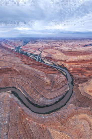 Stunning aerial view of a winding river cutting through a vast desert in San Juan canyon. The rich