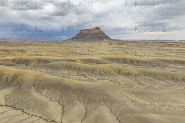 Vast desert landscape with a solitary rock formation under a dramatic sky in Hanskville, Utah. The