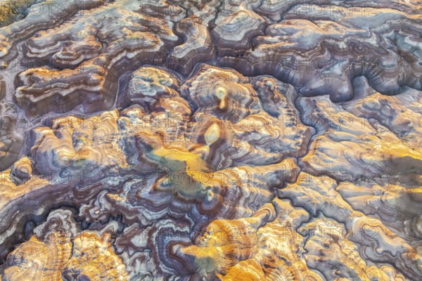 Aerial view of bentonite formations in Utah, USA, showcasing golden and earthy tones. The intricate