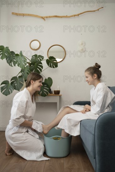 A mother and daughter in cozy bathrobes enjoy a relaxing home spa day. The mother pampers her