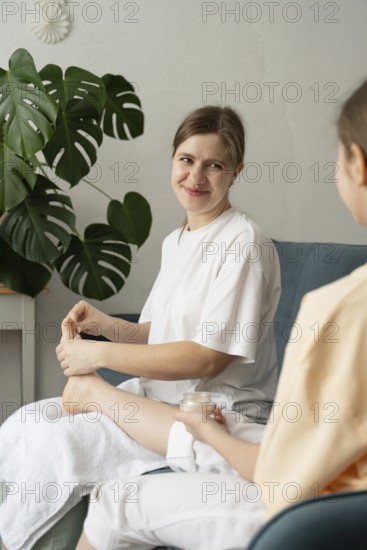 A mother and daughter share a bonding moment as they pamper each other with foot care in a cozy