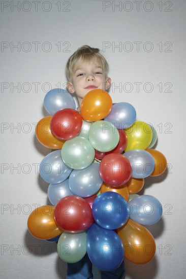 A cheerful child is standing with a delightful expression, almost hidden behind a vibrant bunch of