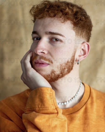 A close up portrait of a stylish young man with red curly hair, wearing a pearl necklace and