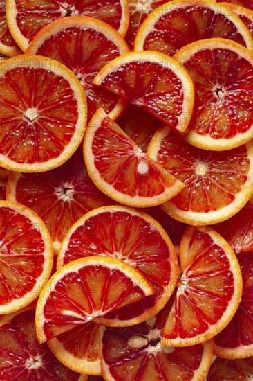 A close-up view of freshly sliced blood oranges revealing vibrant red and orange hues. The juicy