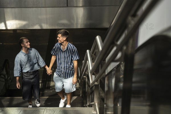 A happy gay couple, hand in hand, strolling up a stairway in the vibrant streets of Madrid.