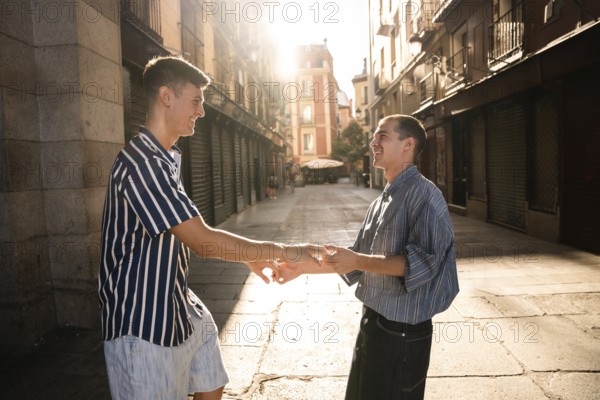 A joyful gay couple holding hands under warm sunlight on a sunny street in Madrid, capturing an