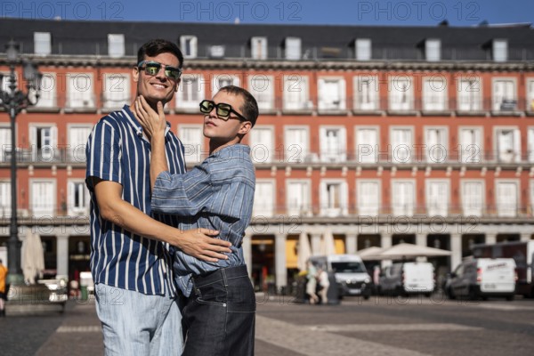 A joyful gay couple embraces on a sunny day in the vibrant streets of Madrid. Their expressions