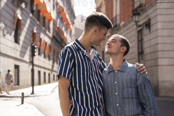 A joyful gay couple embraces while strolling through the picturesque streets of Madrid. Their