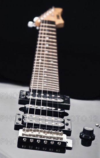Close up of an electric guitar showcases sleek design and detailed focus on strings. Emphasizes