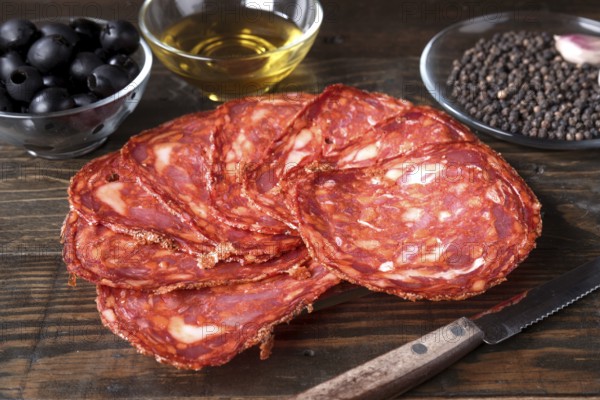 Sliced spanish cured chorizo artfully arranged on a rustic wooden table, accompanied by a bowl of