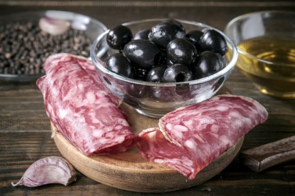 A savory Mediterranean antipasto featuring sliced spanish salami, black olives, garlic, and olive