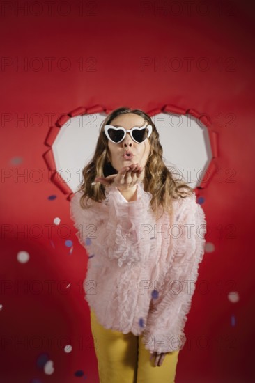 A charming woman with long hair wearing heart-shaped sunglasses and a frilly pink blouse sends a
