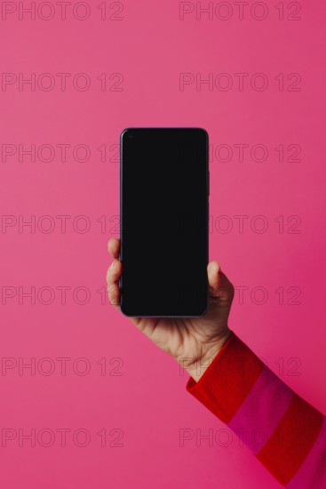 Crop anonymous person in casual clothes showing modern smartphone with empty screen while standing