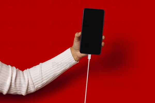 Side view of unrecognizable person in casual clothes holding smartphone with black screen while