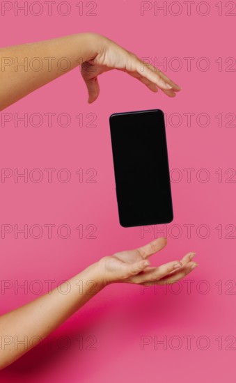 Crop anonymous person in casual clothes showing modern smartphone with empty screen while floating