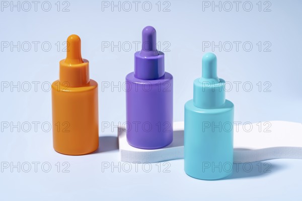 Three serum bottles in vibrant orange, purple, and turquoise colors, showcased against a soft blue
