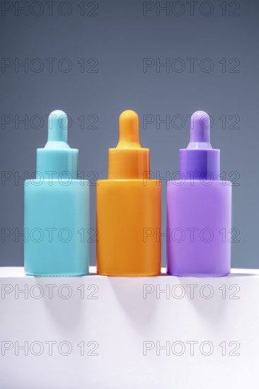 Three vibrant and colorful serum bottles aligned on a sleek surface with a soft gray gradient