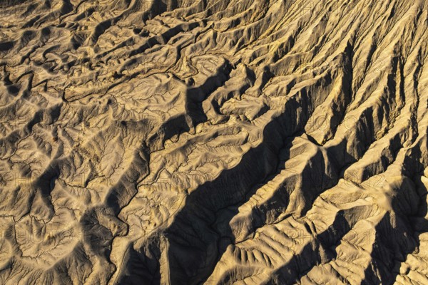 Aerial view of golden desert textures at Caineville Mesa, Utah. Features notable ridges and