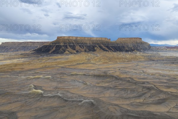 A breathtaking view of a desert plateau rising under a vast, cloudy sky, showcasing layers of