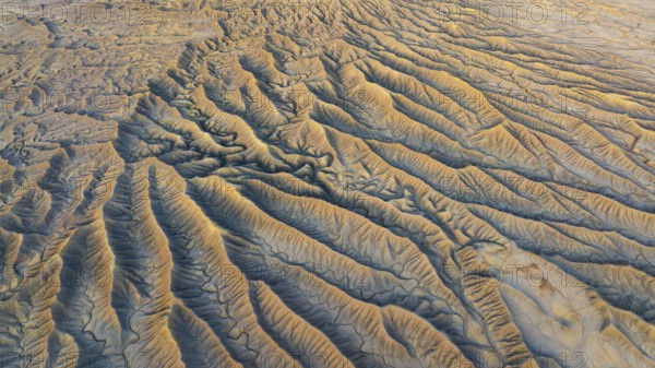 Aerial view of Caineville Mesa's rugged landscape. Eroded valleys and golden hues capture the