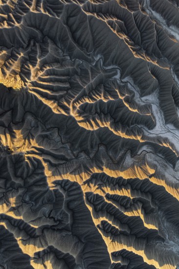 Aerial photo capturing golden desert textures and intricate patterns of Caineville Mesa, Utah. The