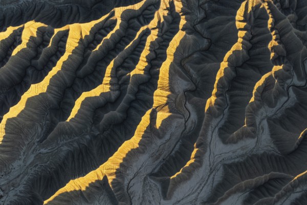 Aerial view of Caineville Mesa, Utah, showcasing dramatic ridges illuminated by golden sunlight.